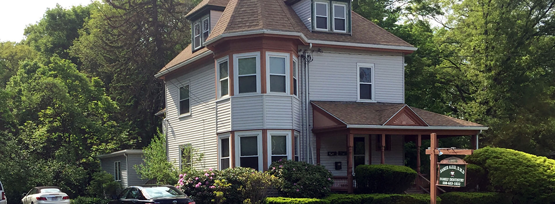 The image shows a two-story house with a prominent front porch, white siding, and a gray roof.