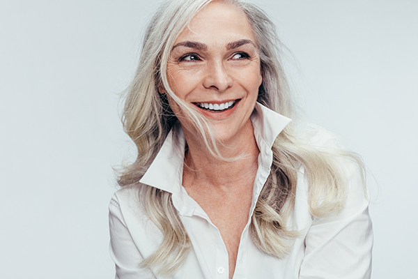 A woman with short hair, wearing a white shirt, smiling at the camera.