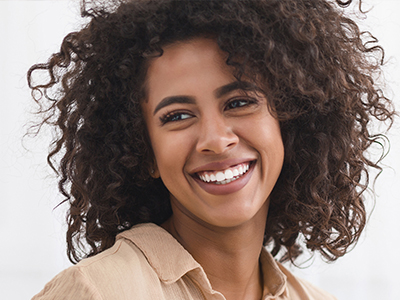 A young woman with curly hair smiling at the camera.